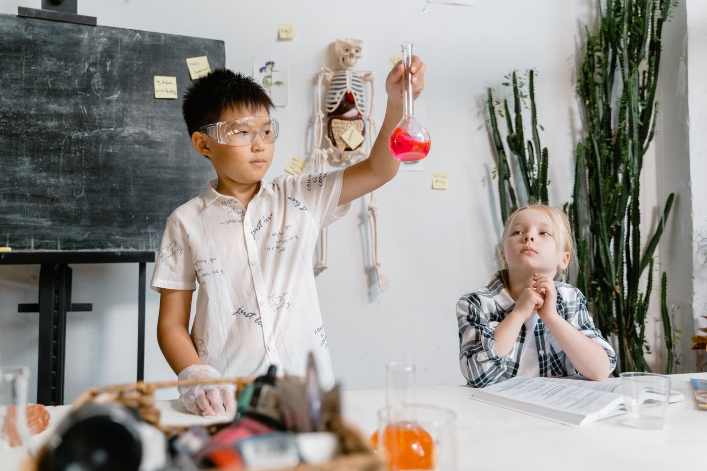 A student in safety goggles holds up a flask of red liquid during a chemistry experiment